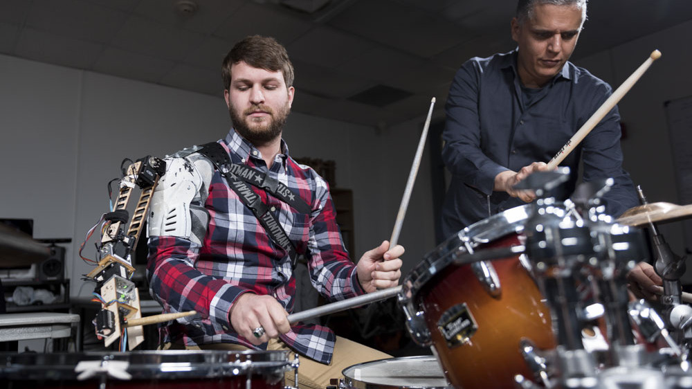Gil Weinberg with Tyler White playing drums with a robotic arm
